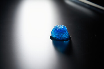 A piece of beautiful blue ice on a matte surface with backlight