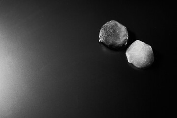 Black and white photo of a two pieces beautiful ice on a matte surface with backlight top view