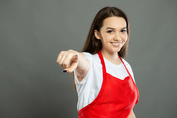Portrait of young attractive female supermarket employee pointing camera