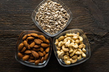Almond, sunflower seeds and cashew in a small plates which standing on a vintage wooden table. Nuts is a healthy vegetarian protein and nutritious food.