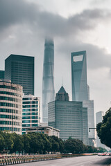 The traffic on central avenue, with modern skyscrapers in the back, in Shanghai, China, shot at sunset, on a cloudy day.