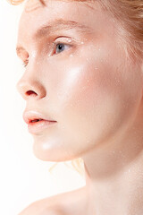 Shining creative makeup in bright colors. Closeup portrait of a young blonde with radiant make-up with highlighter.