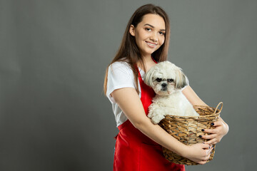 Young female supermarket employee holding basket with cute dog
