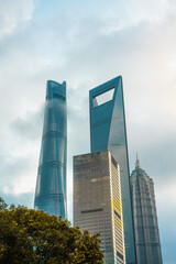 Obraz premium Modern skyscrapers in Lujiazui, the financial district in Shanghai, shot on a cloudy day, at sunset.