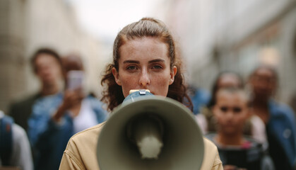 Female activist protesting with megaphone during a strike - obrazy, fototapety, plakaty
