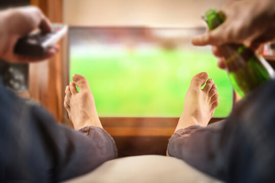 man watching match on tv with remote and beer