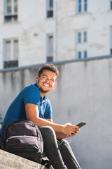 smiling young mixed race african american man listening to music with earphones and cellphone