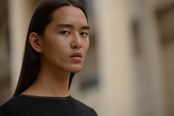 Face of young Asian man with long hair in the city