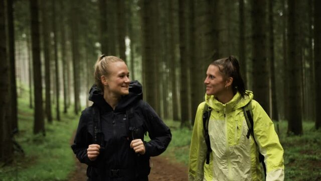 Two girls hiking through the forest in the rain