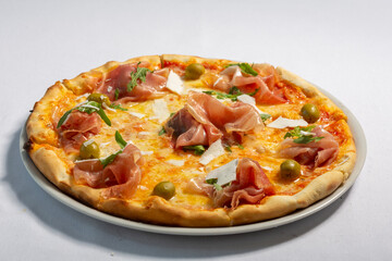 Prosciutto pizza served on white plate