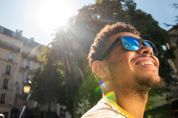 happy young african american mixed race man with sunglasses in the city looking up