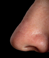 Close up of a man's nose isolated on a black background.