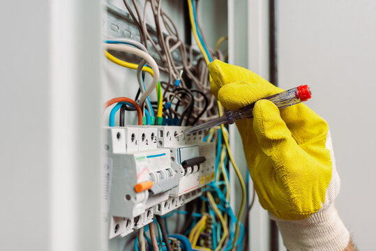 Selective focus of electrician using screwdriver while fixing electric panel