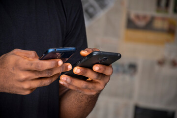 Fototapeta premium closeup of a young african man using two mobile phones at the same time