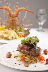 Steak with bacon and linguine and a lobster main course in the background