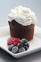 Chocolate chip muffin with whipped cream and berries