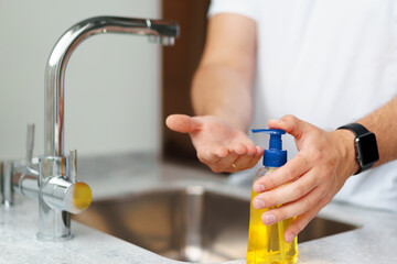 Man washing hands with soap in a sink at his home