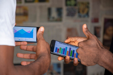 two young people viewing graph information on their mobile phones , contemplating ideas, planning