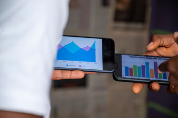 two africans viewing graph information on their mobile phones , contemplating ideas, planning