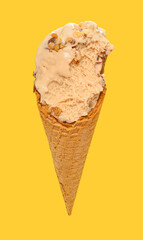 angle view milk tea flavor ice cream cone with some bites on a yellow background