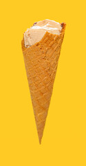 side view milk tea flavor ice cream cone with some bites on a yellow background