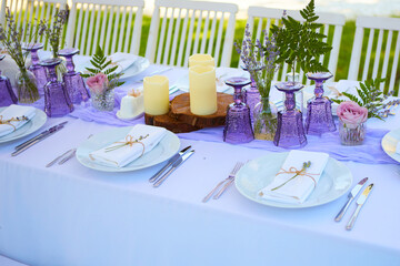 Elegant table setting for wedding engagement Easter dinner with white ceramic plates cotton napkin tied with twine lavender flowers candles. Provence style