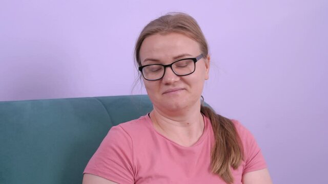 Funny young female wearing casual pink shirt and eyeglasses makes the helpless gesture with both hands, looking at something down. Strong emotions.