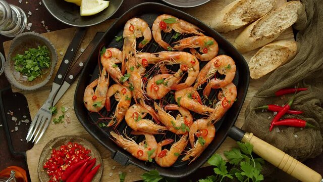 Grilled shrimps in cast iron grilling pan with fresh lemon, parsley, chili, garlic white wine sauce