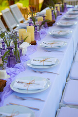 Elegant table setting for wedding engagement Easter dinner with white ceramic plates cotton napkin tied with twine lavender flowers candles. Provence style