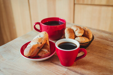 Two cups of black coffee and croissant on a wooden board