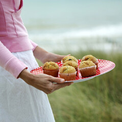 Woman holding a tray of muffins