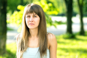 Naklejka premium Portrait of serious pretty young woman in summer park.