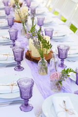 Elegant table setting for wedding engagement Easter dinner with white ceramic plates cotton napkin tied with twine lavender flowers candles. Provence style