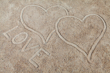 The word Love written in sand with signed hearts