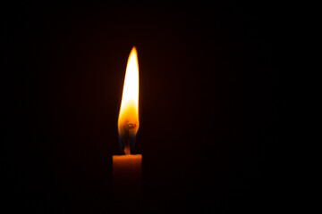 Close up single candle light and flame on black background