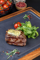 Steak mignon with fresh herbs on a black slate blackboard