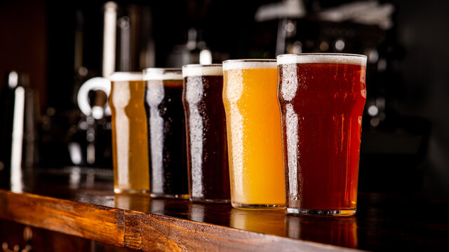 Many varieties of craft beer. Misted glass goblets with ale, lager, and unfiltered drink on bar