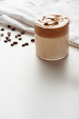 selective focus of delicious Dalgona coffee in glass near coffee beans and napkin on white background