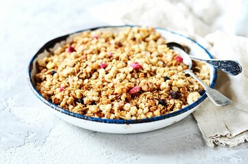 Homemade granola with berries and nuts in a bowl on a gray background