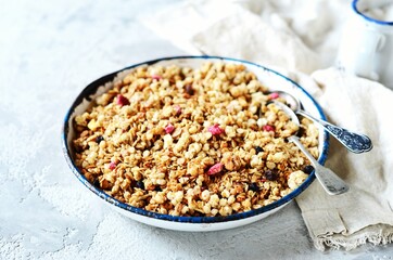Homemade granola with berries and nuts in a bowl on a gray background