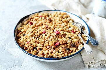Homemade granola with berries and nuts in a bowl on a gray background