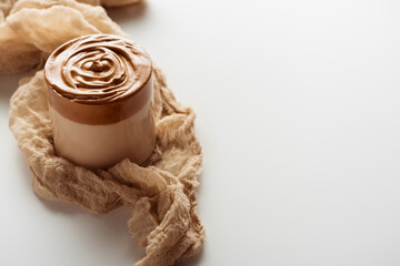 delicious Dalgona coffee in glass on cloth on white background