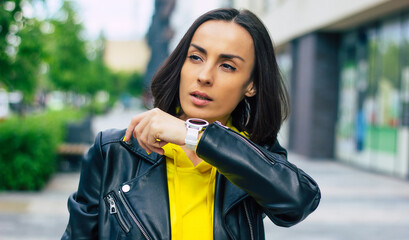 New modern technologies! A half-length photo of a young businesswoman on the street, that possesses a smartwatch, smartphone, wireless headphones.