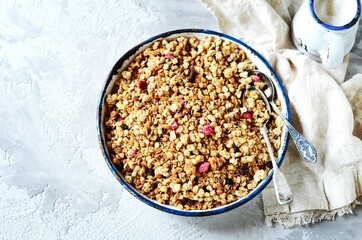 Homemade granola with berries and nuts in a bowl on a gray background