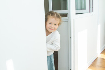 Little cute girl in a bright room, a minimum of objects in the room, the child rejoices, sitting on...