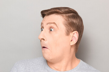 Fototapeta premium Portrait of funny surprised confused mature man with raised eyebrows
