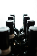 Dark wine bottles stand in a row in backlight