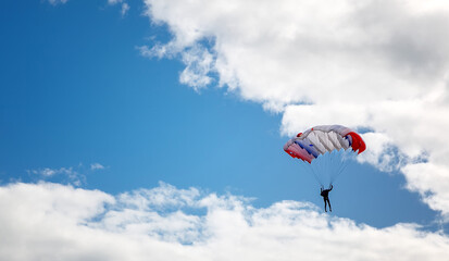 Fototapeta na wymiar skydiver high in the clouds, blue streak of sky
