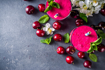 Sweet cherry smoothie drink in glass jars with mint leaves and fresh berries