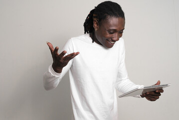 Happy young handsome African man with dreadlocks using digital tablet